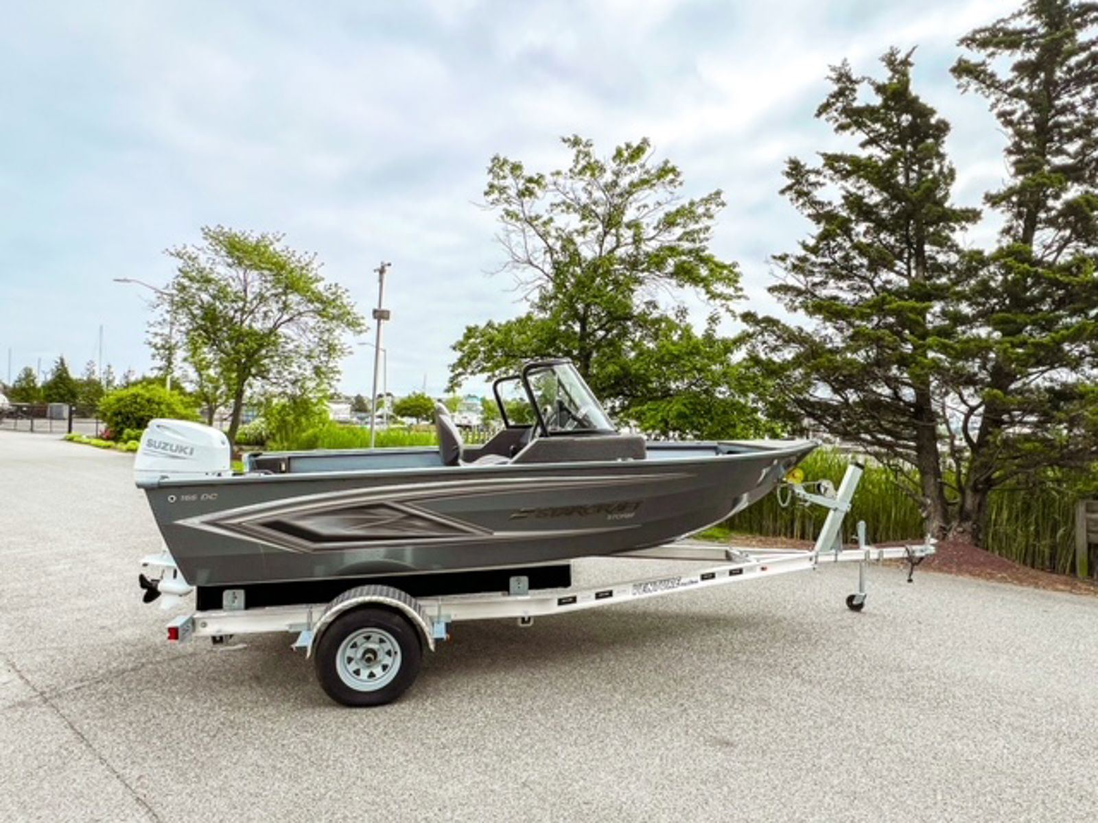 Starcraft Storm 16 DC aluminium fishing boat in side profile on its trailer, with grey hull graphics, wrap-around windshield and outboard