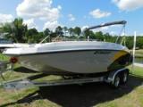 Starcraft SVX 171 deck boat on a twin-axle trailer on grass, with a white hull, black and yellow graphics and a bimini top
