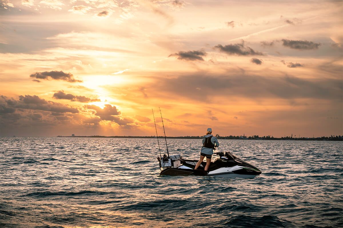 Rider standing on the Kawasaki Jet Ski Ultra 160LX-S Angler at sunset