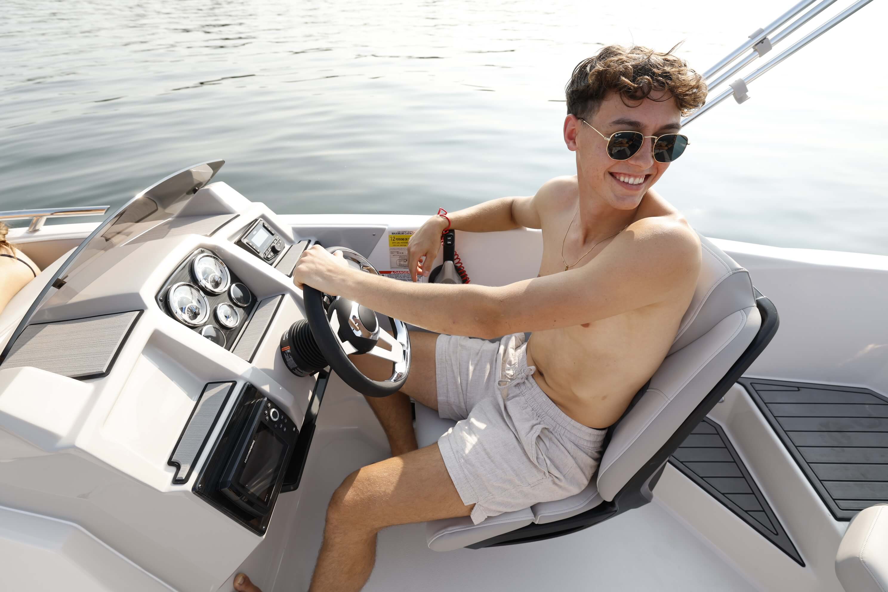 Smiling driver at the helm of a Starcraft SVX 191 OB, showing the steering wheel, gauges, dash and bucket seat