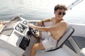Smiling driver at the helm of a Starcraft SVX 191 OB, showing the steering wheel, gauges, dash and bucket seat