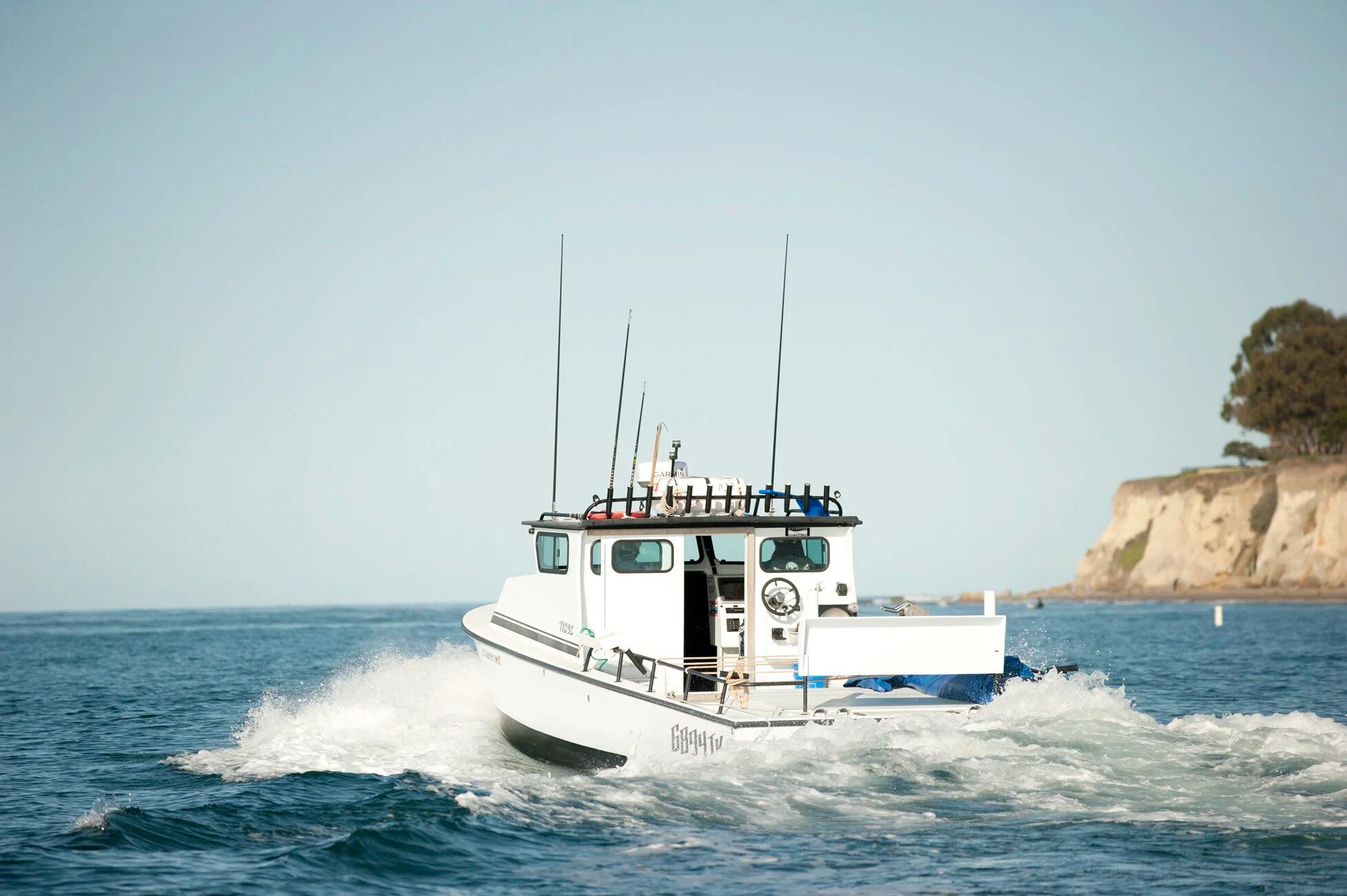 White Anderson 31 pilothouse turning at speed near a coastal headland