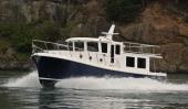 American Tug 395 cruising past a rocky shoreline