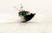Dark-green Anderson 31 commercial fishing boat launching through spray at speed
