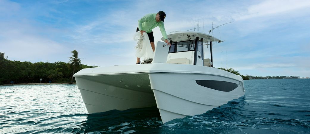 Angler on the bow of the Aquila 28 Molokai, showing the twin hulls