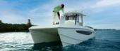 Angler on the bow of the Aquila 28 Molokai, showing the twin hulls