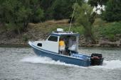 Blue-hulled Greenough 21 pilothouse with single Suzuki outboard cruising along a riverbank