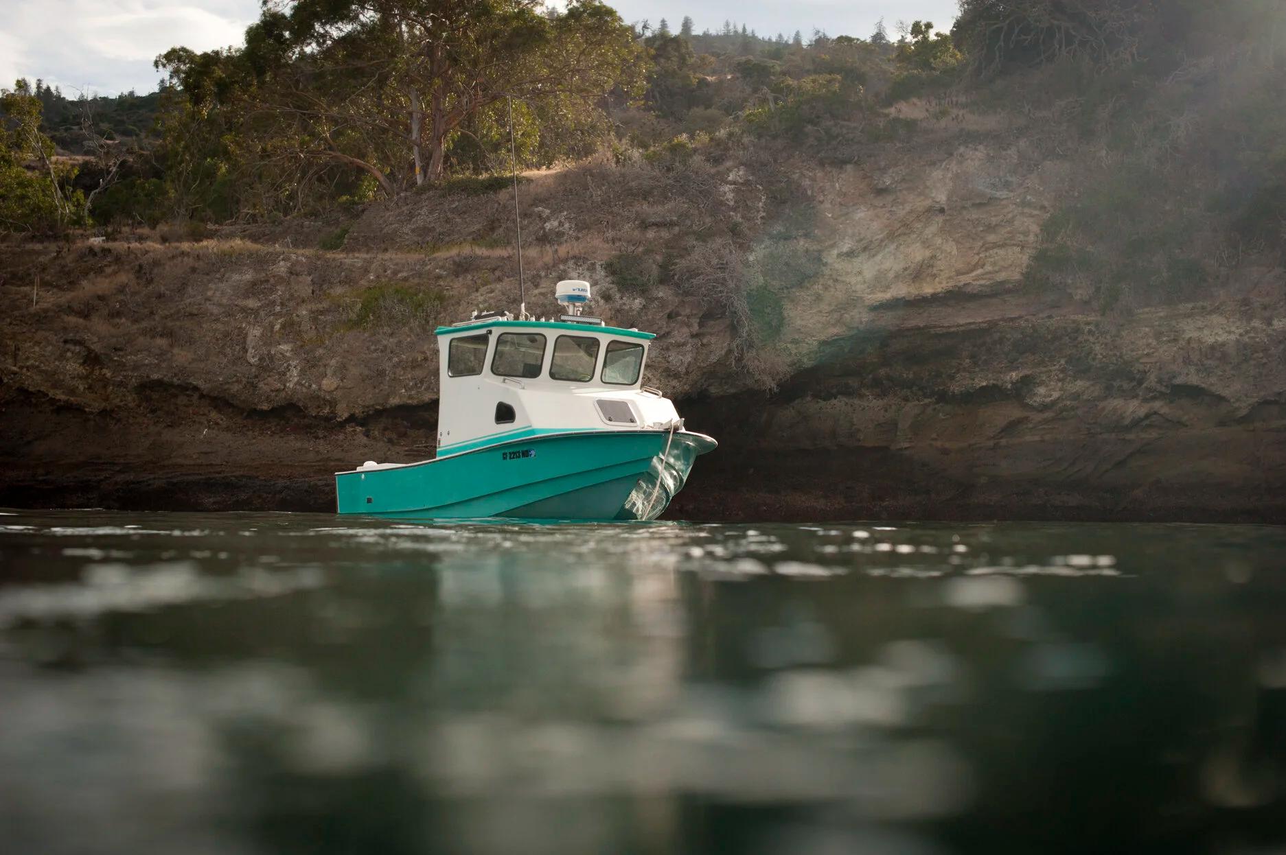 Teal Anderson 22 pilothouse moored beneath a rocky sea cliff
