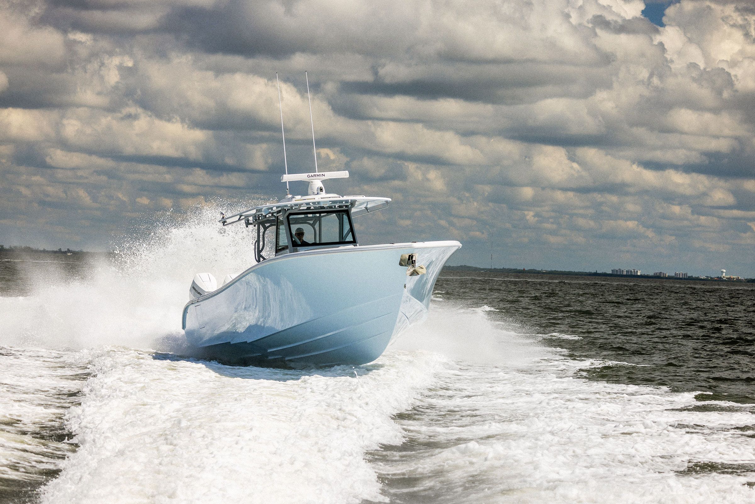 Yellowfin 39 Offshore running bow-on with a wide wake under a cloudy sky