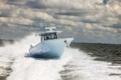 Yellowfin 39 Offshore running bow-on with a wide wake under a cloudy sky