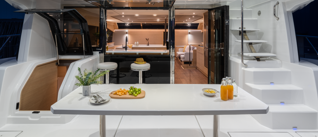 Aquila 54 Yacht aft cockpit with dining table, opening onto the galley and salon