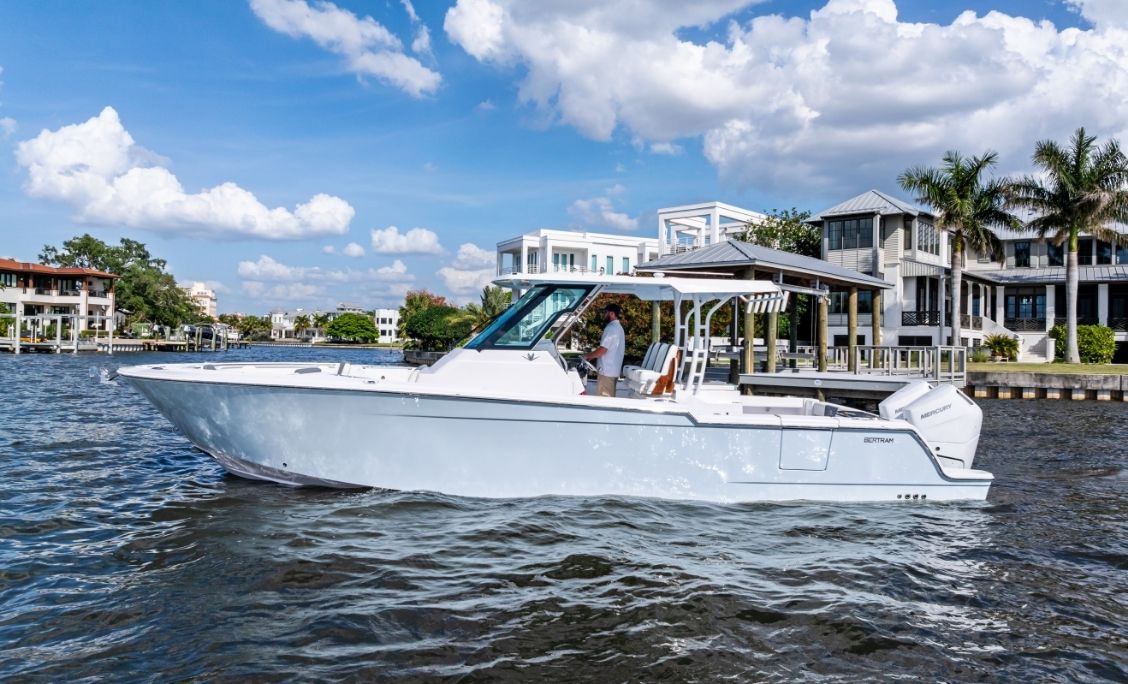 Bertram 34CC cruising past waterfront homes with guests aboard