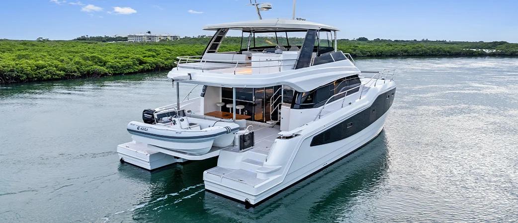 Aquila 50 Yacht at anchor with tender off the stern, showing high freeboard and flybridge