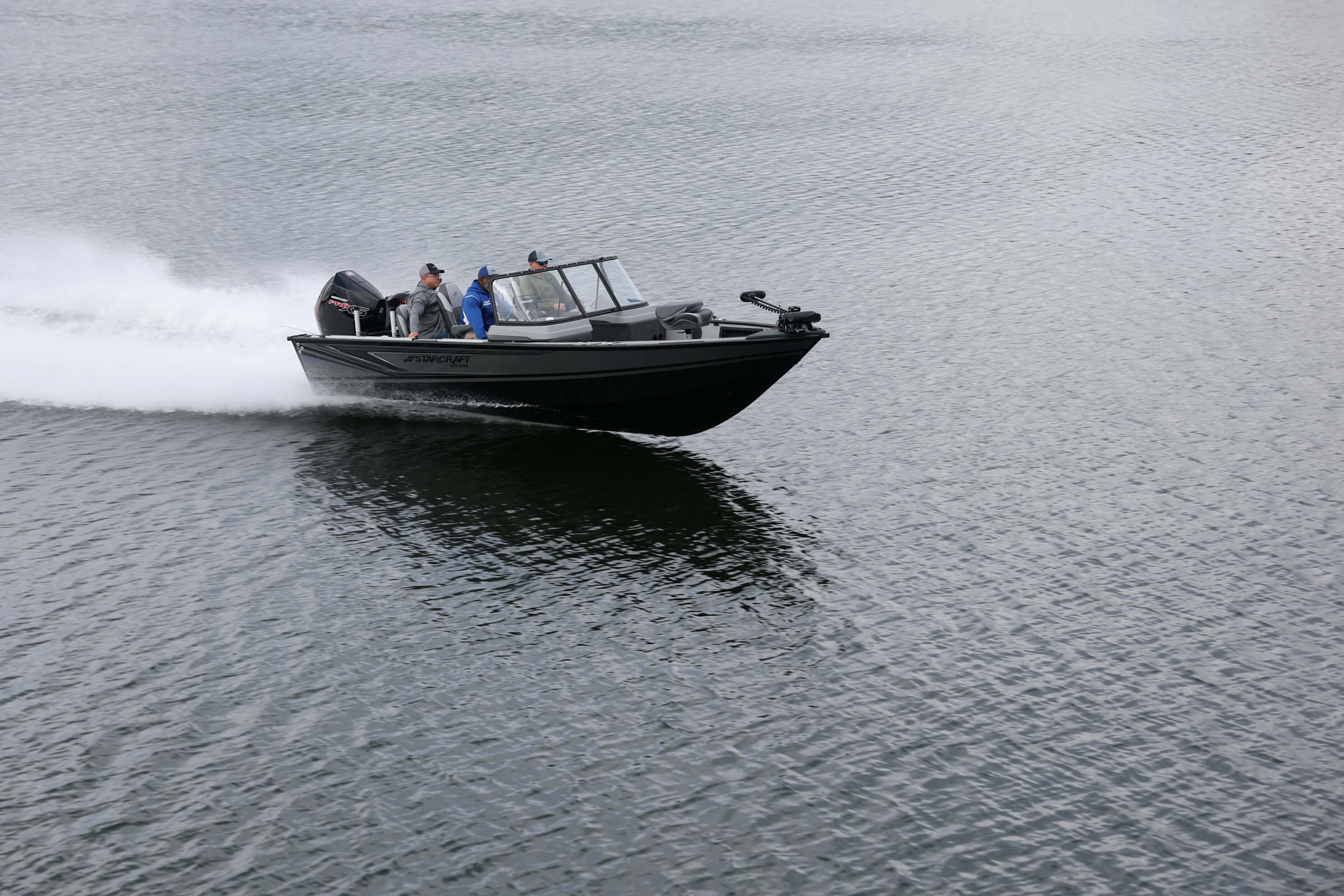 Starcraft STX 2050 planing across dark open water, throwing a bow wave behind it