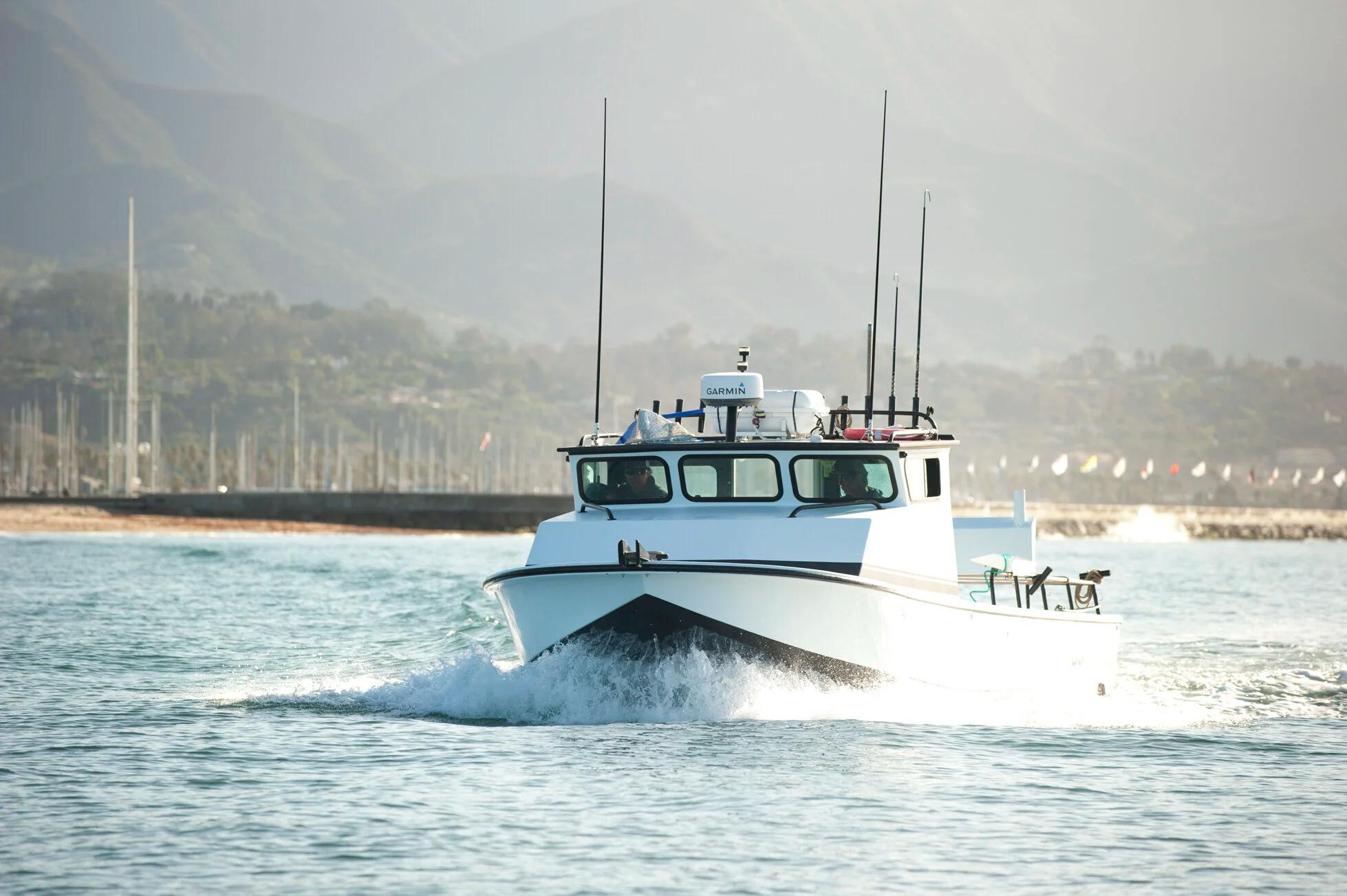 White Anderson 31 pilothouse running head-on out of a harbour