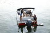 Stern view of a Starcraft SVX 191 OB with its outboard motor as a young skier prepares to waterski behind the boat