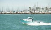 Greenough 21 pilothouse rigged with fishing rods heading out from a marina breakwater