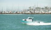 Greenough 21 pilothouse rigged with fishing rods heading out from a marina breakwater