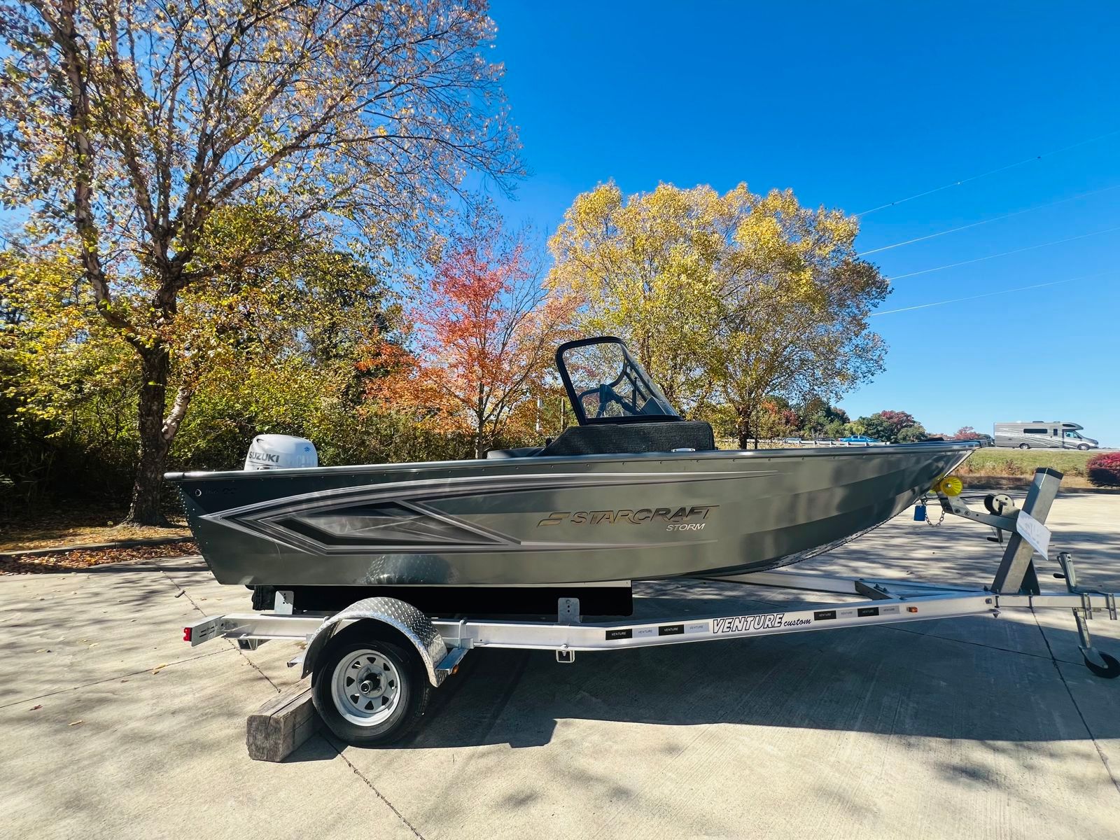 Starcraft Storm 16 DC fishing boat on an aluminium trailer in a car park, with a grey hull, windshield and outboard