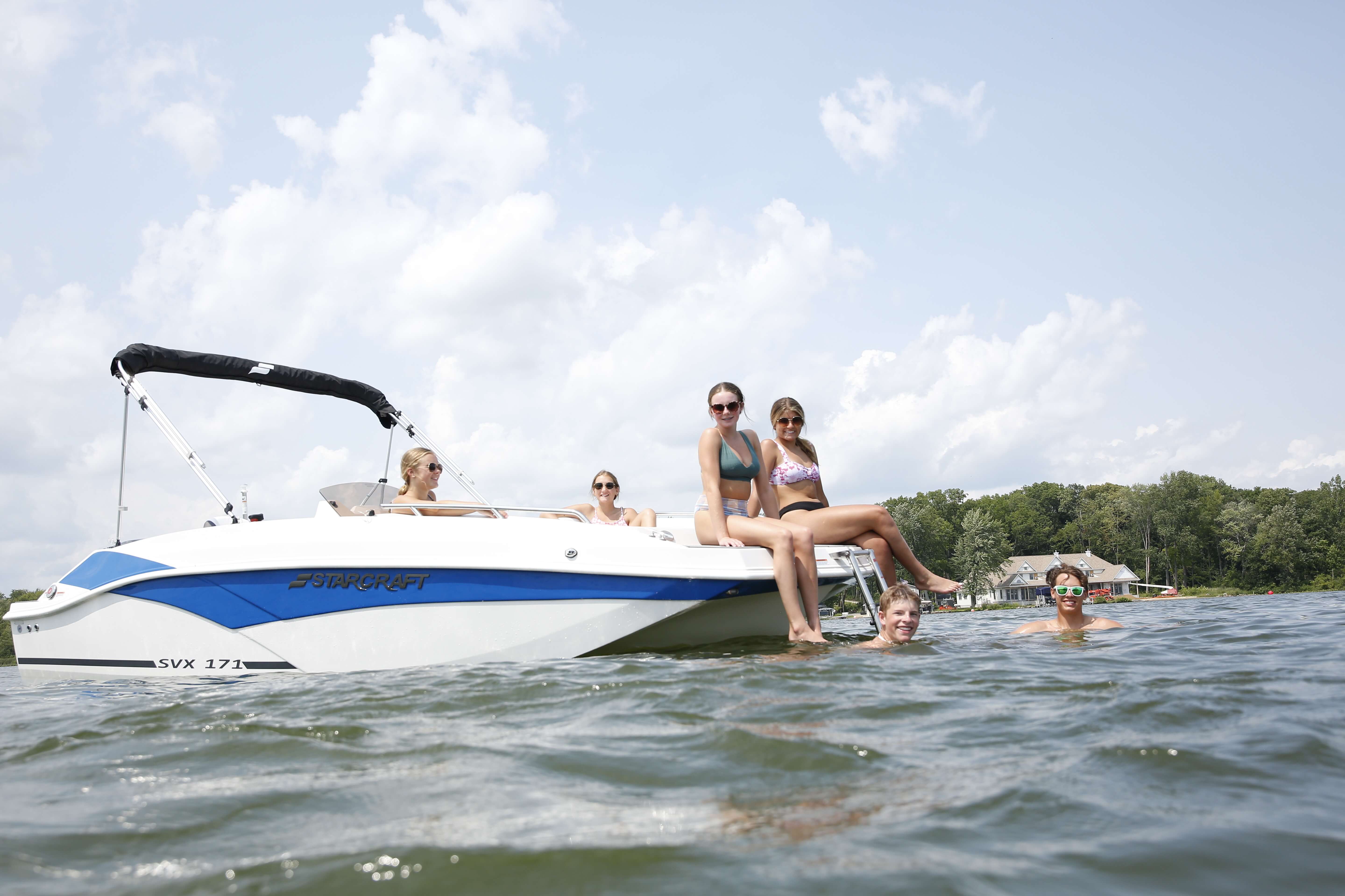 Starcraft SVX 171 OB at anchor on a lake with swimmers in the water and passengers sitting at the stern boarding ladder