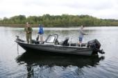 Three anglers fishing from a dark Starcraft STX 2050 with a bow-mounted trolling motor and outboard on a calm lake