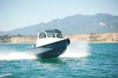 Grey-hulled Greenough 17 pilothouse running at speed with spray off the bow
