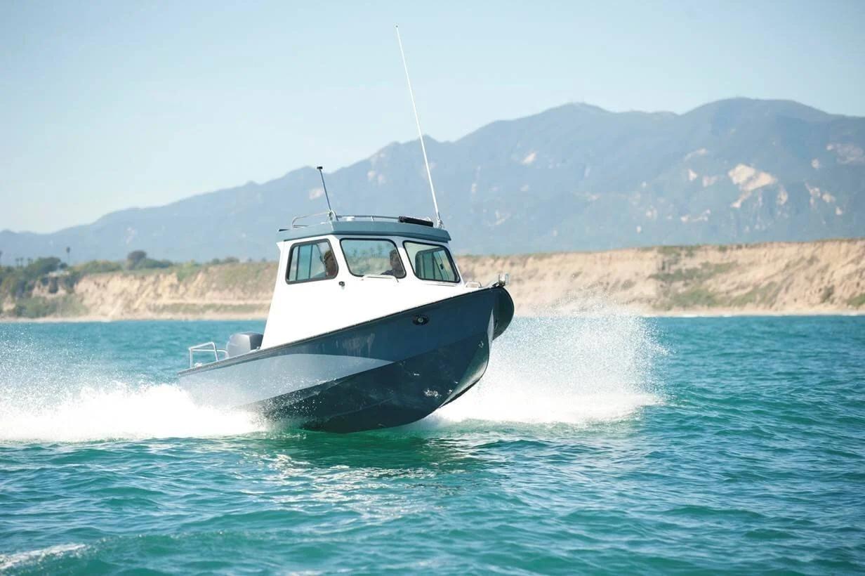 Grey-hulled Greenough 17 pilothouse running at speed with spray off the bow