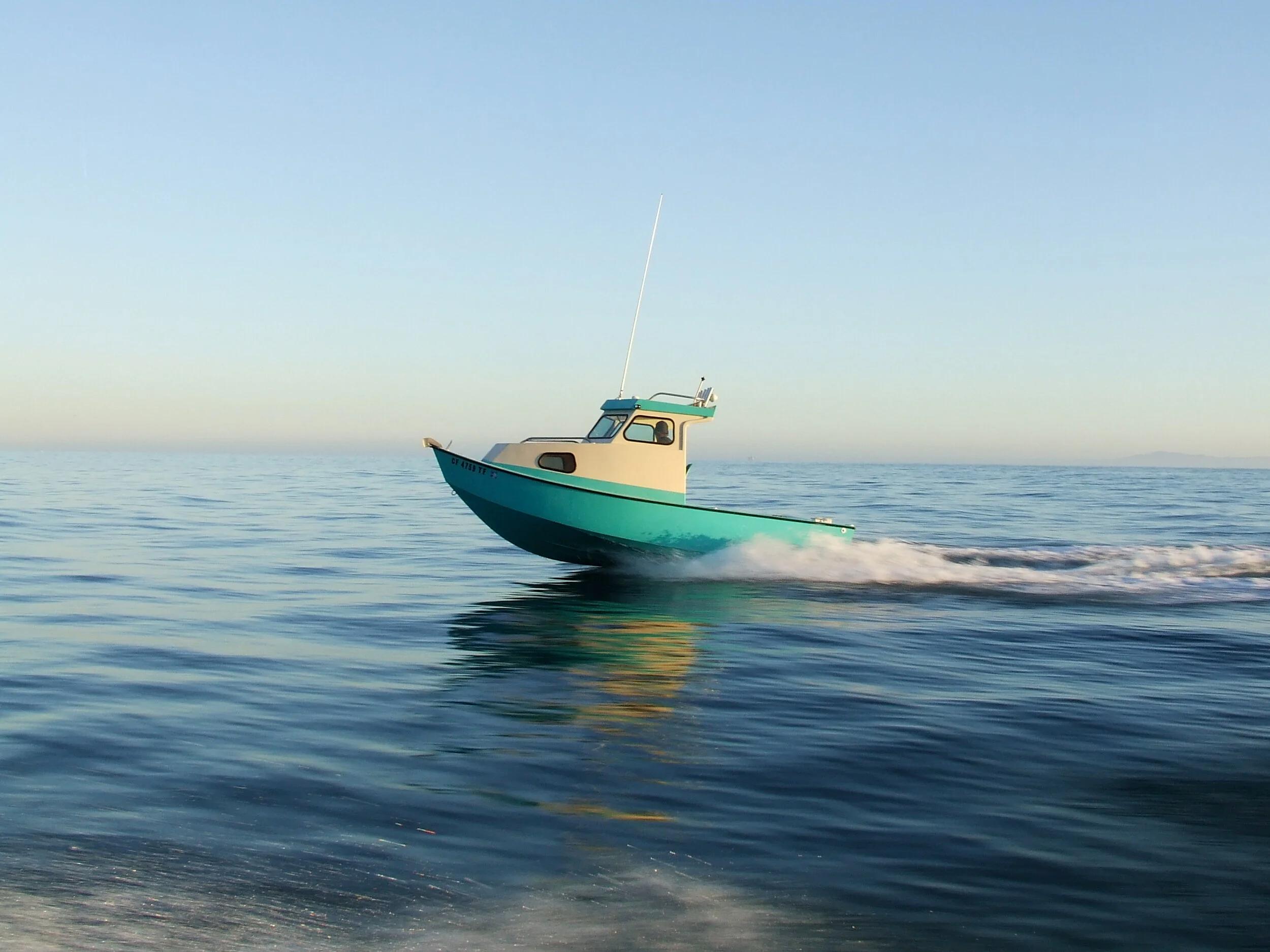 Teal Greenough 17 pilothouse skiff underway on open sea at dusk, side profile