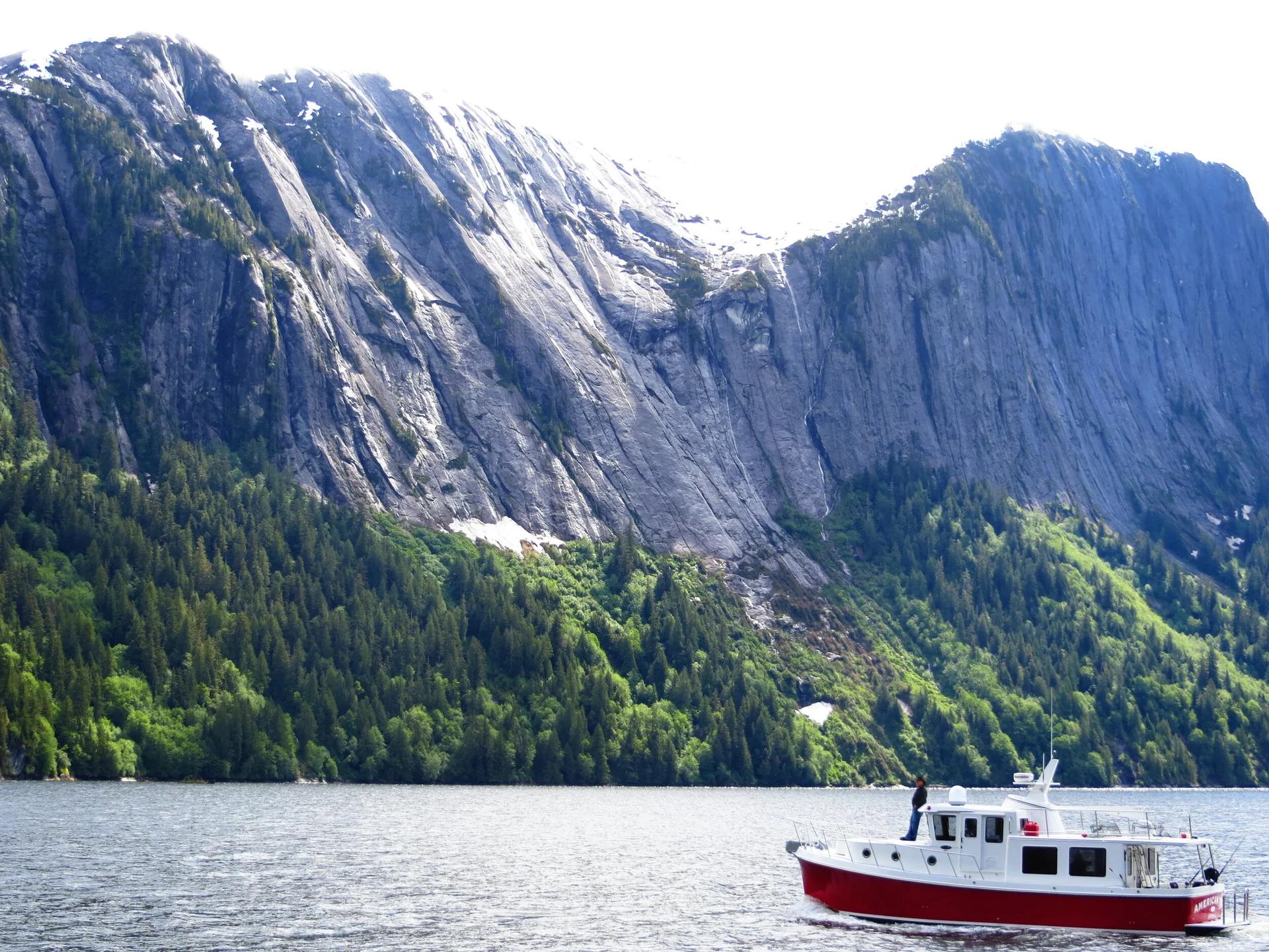 American Tug 395 cruising beneath mountains in a fjord