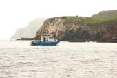 Anderson 26 pilothouse at anchor near a headland on hazy grey water