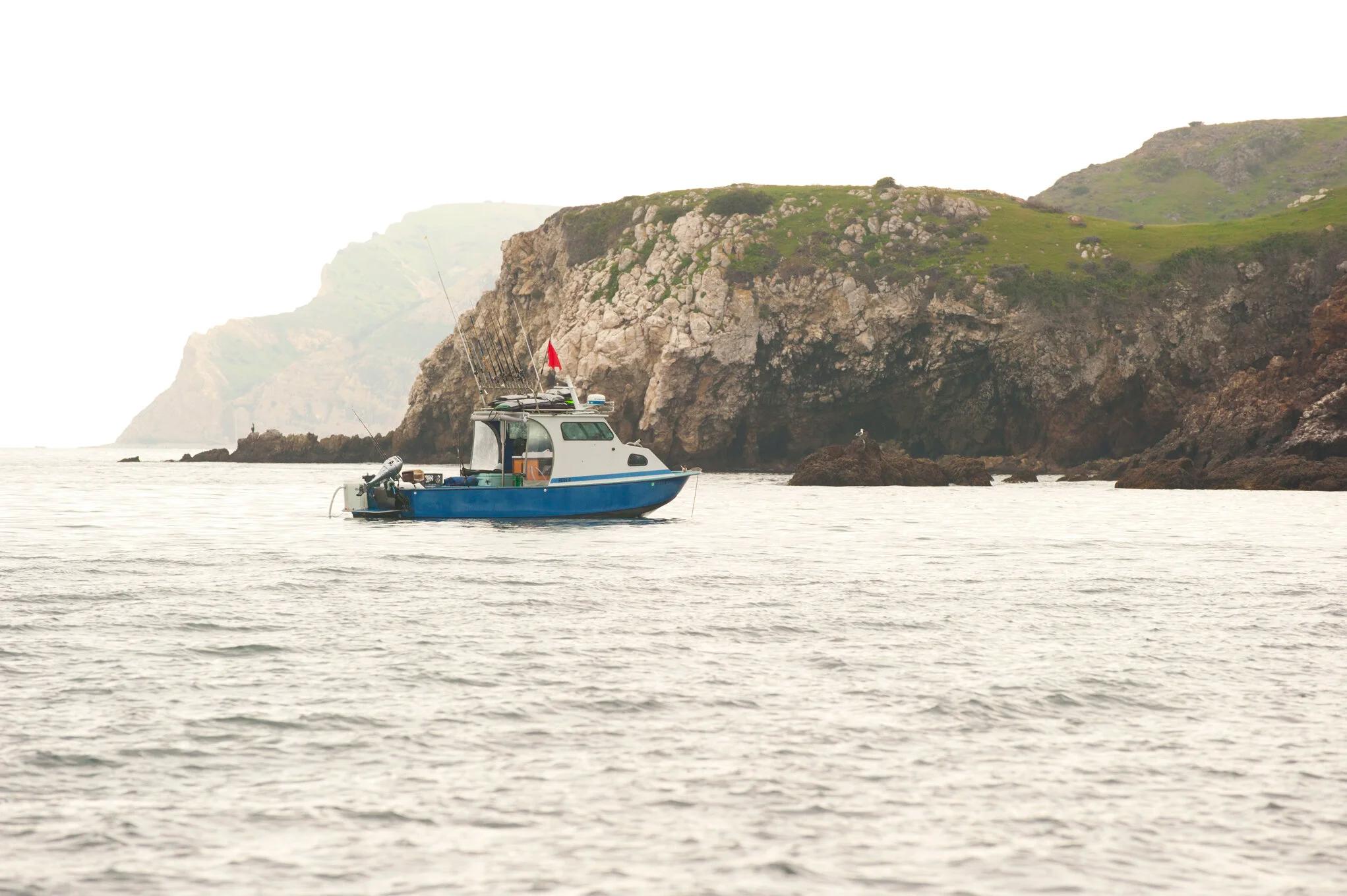 Anderson 26 pilothouse at anchor near a headland on hazy grey water