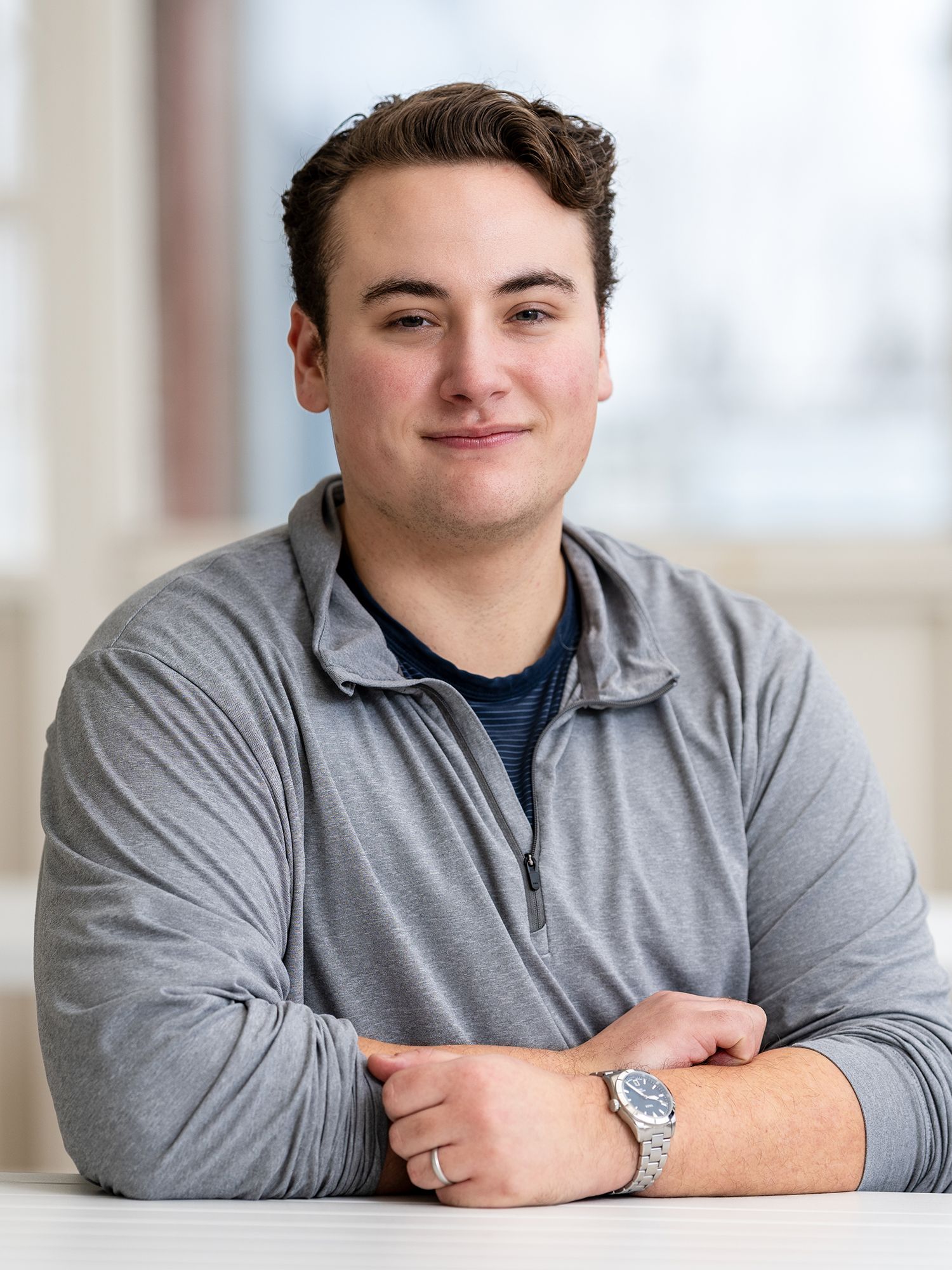 Man in a gray quarter-zip shirt smiling at the camera