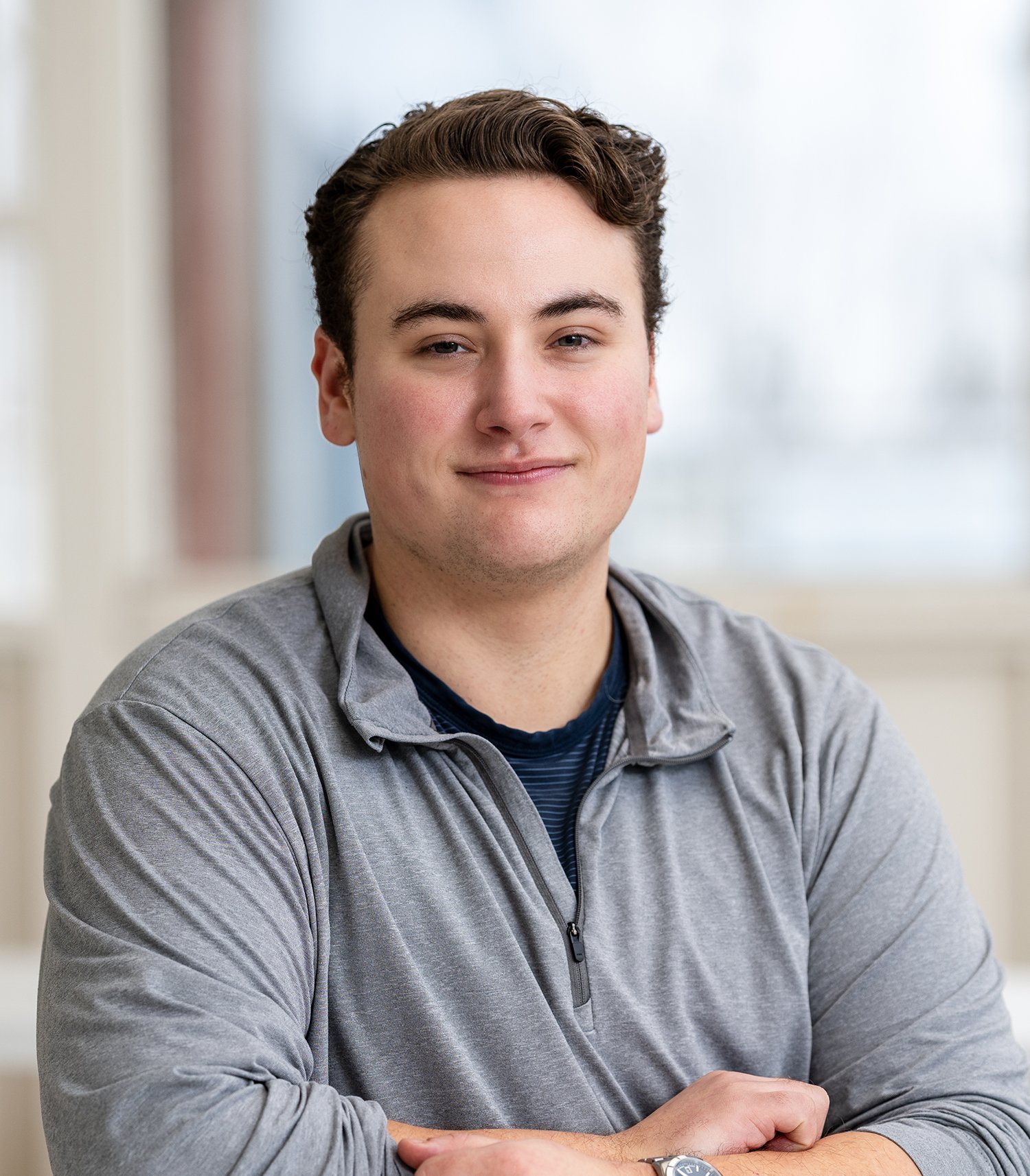 Man in a gray quarter-zip shirt smiling at the camera