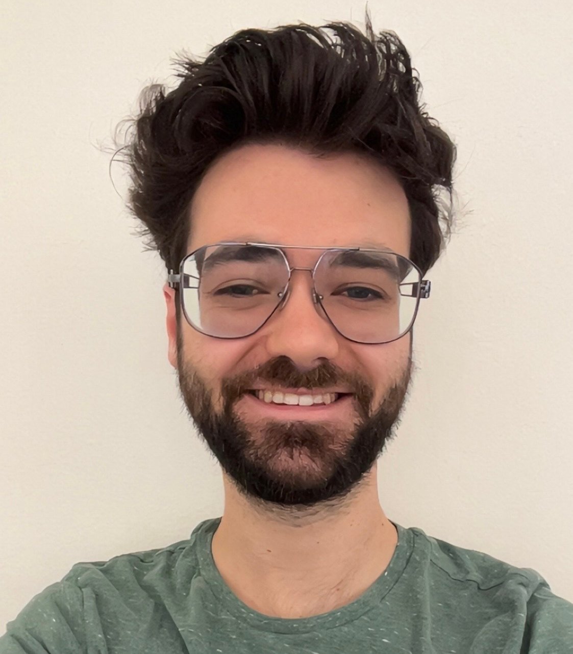 Smiling man with dark hair, beard and glasses