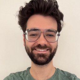Smiling man with dark hair, beard and glasses