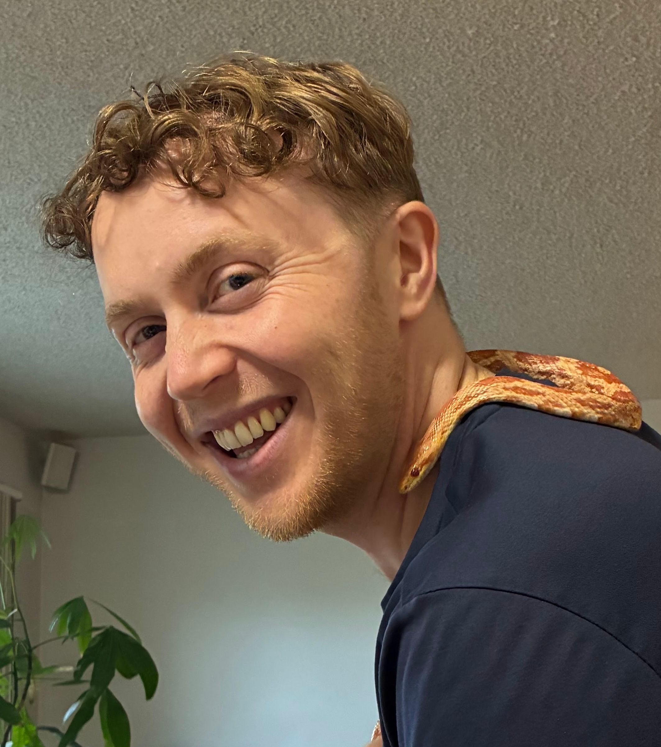 Smiling man with a snake draped over his shoulder