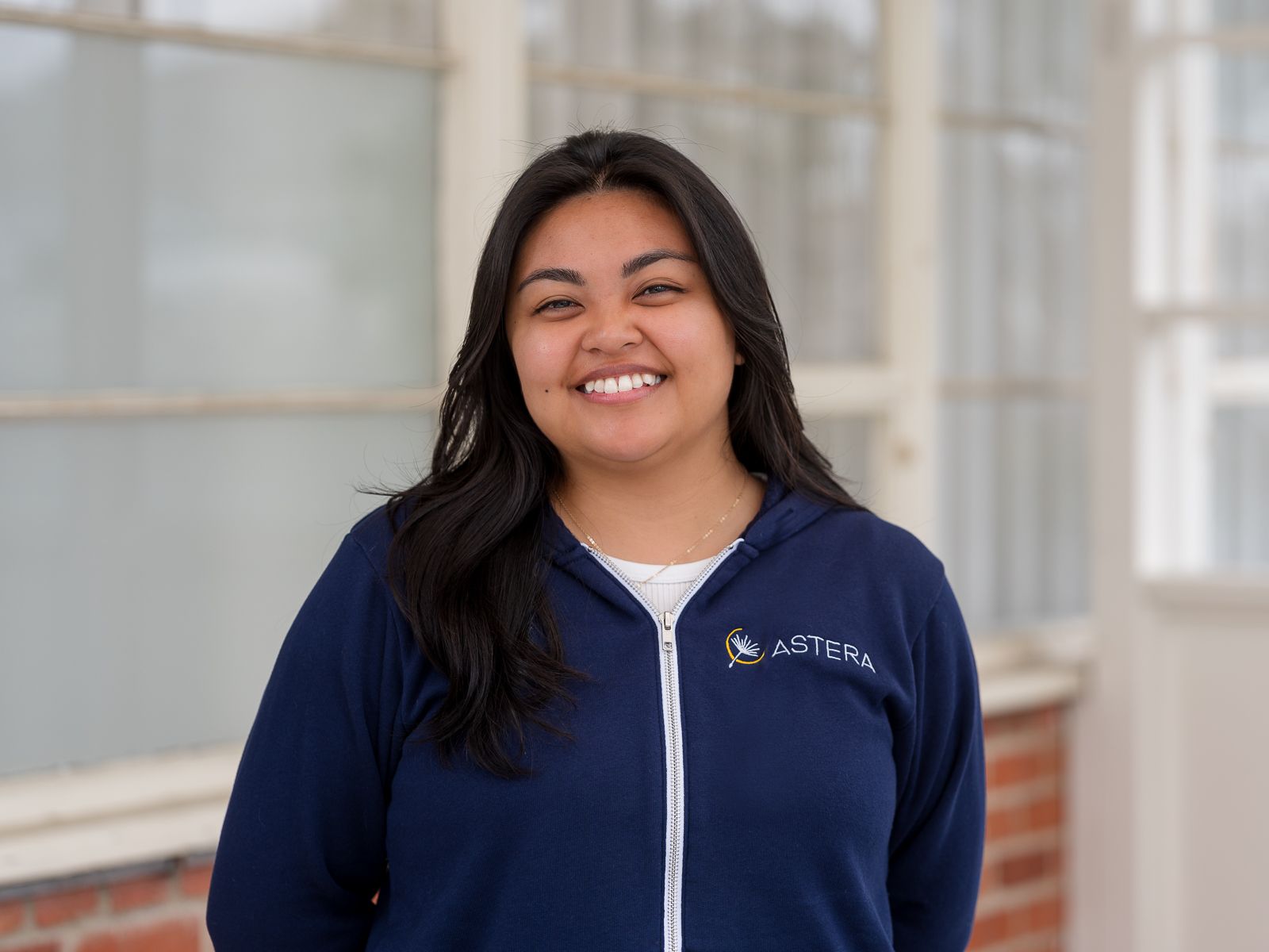 Woman smiling in an Astera zip-up hoodie