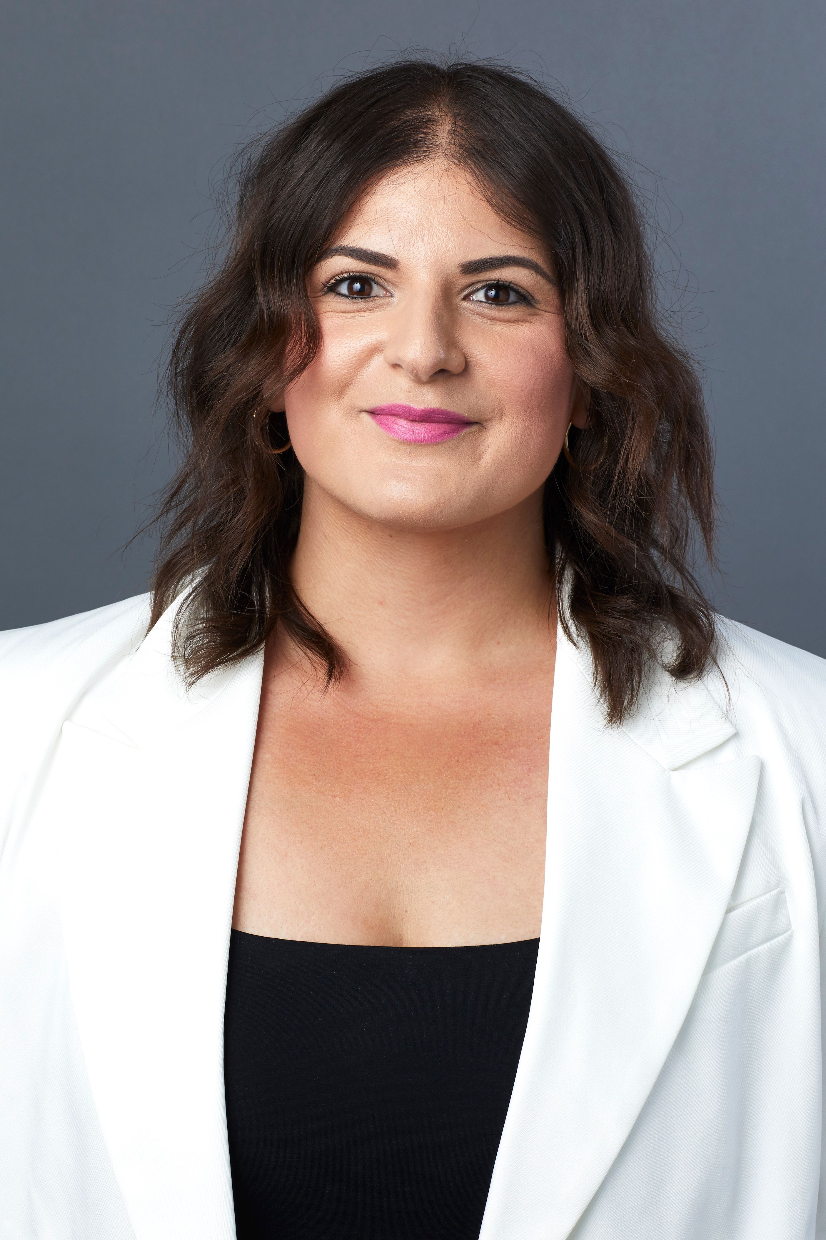 Woman in a white blazer smiling at the camera