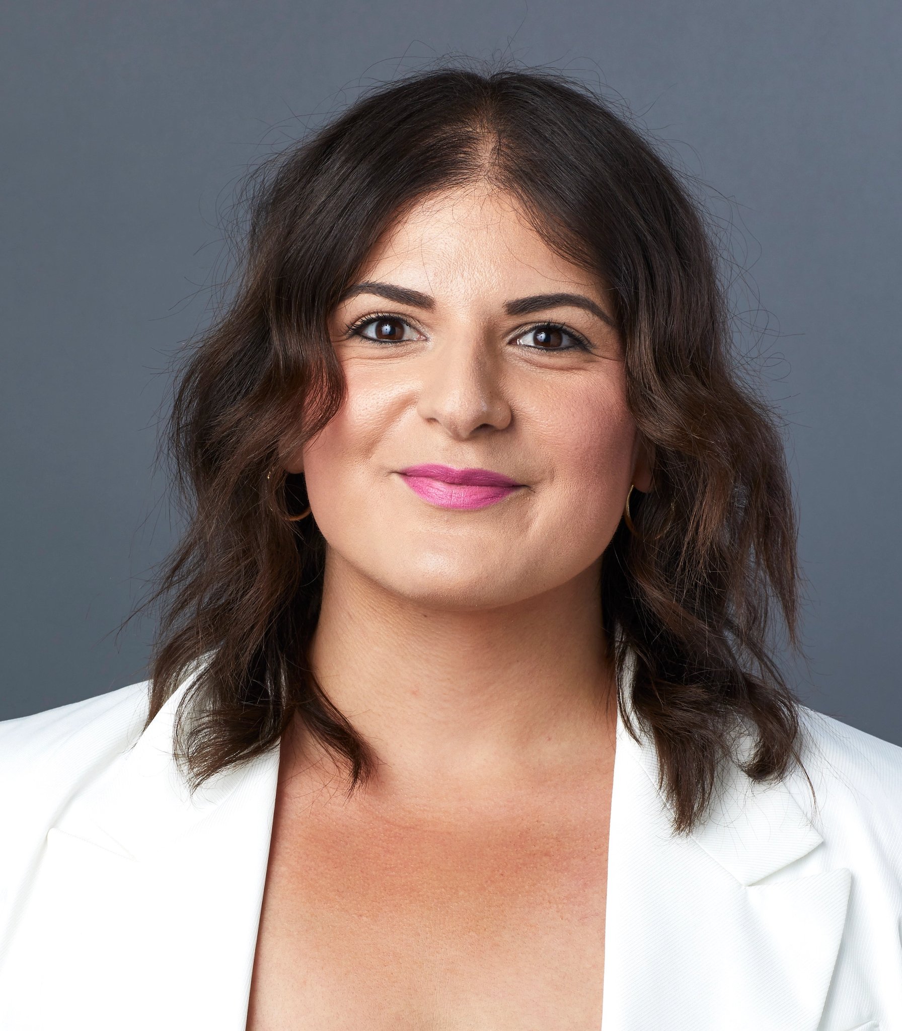 Woman in a white blazer smiling at the camera