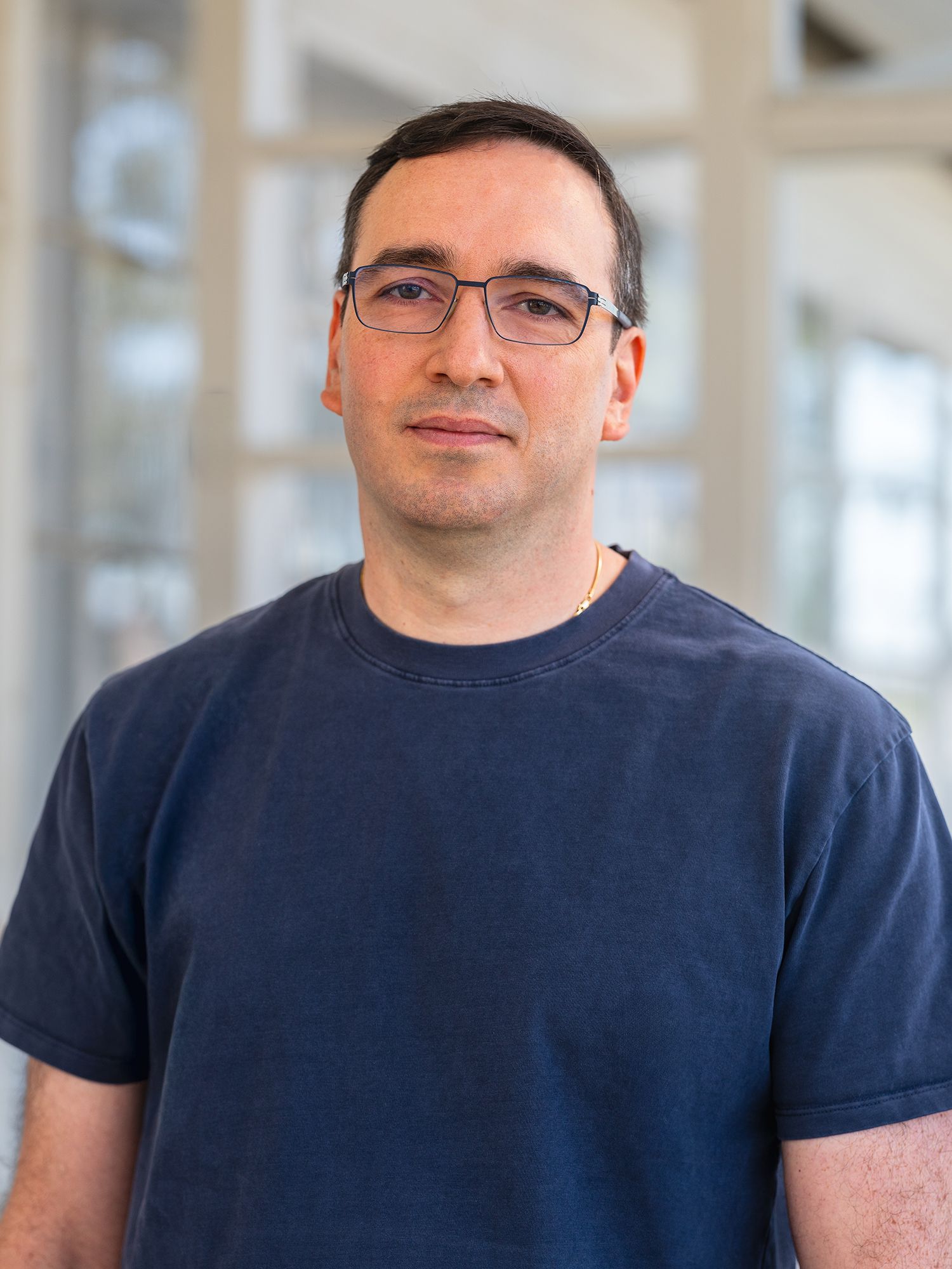 Man wearing glasses and a T-shirt faces the camera
