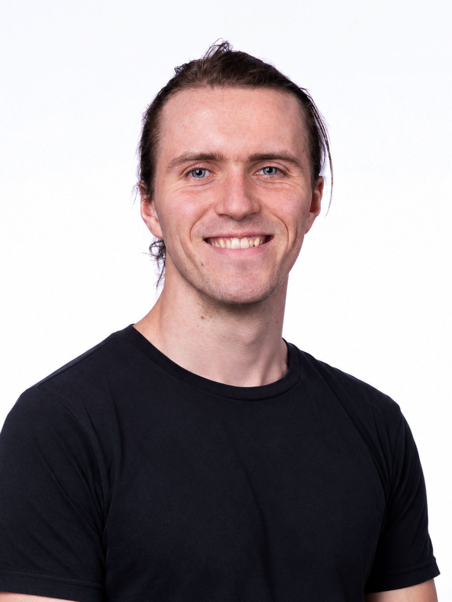 Smiling man with tied-back hair wearing a black T-shirt