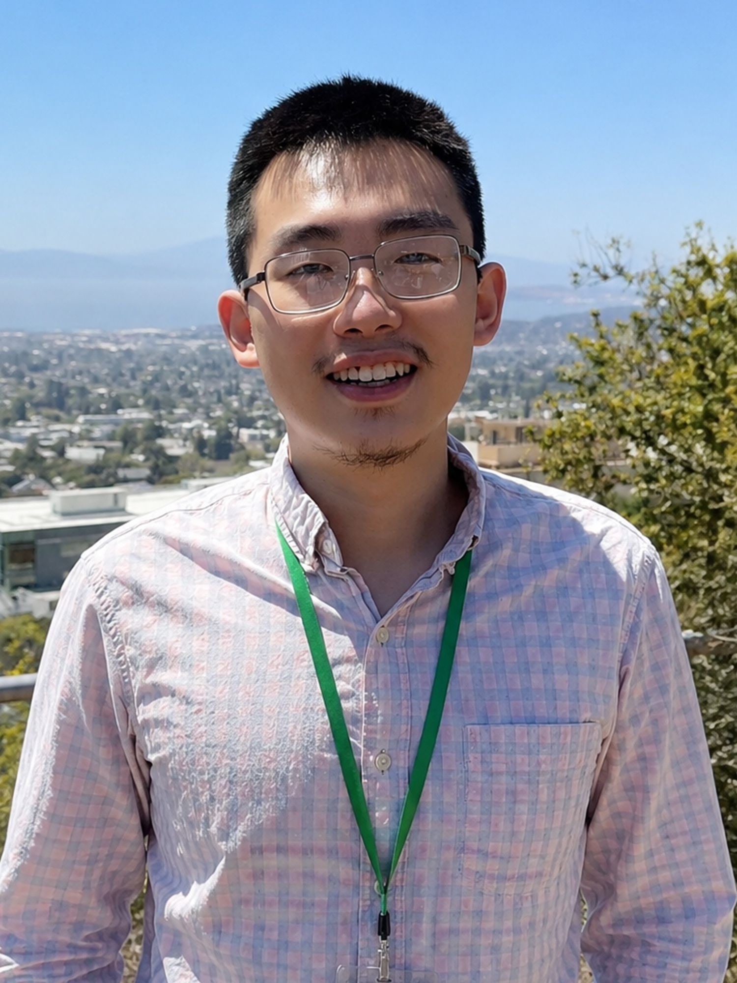 Smiling man wearing glasses and a lanyard outdoors