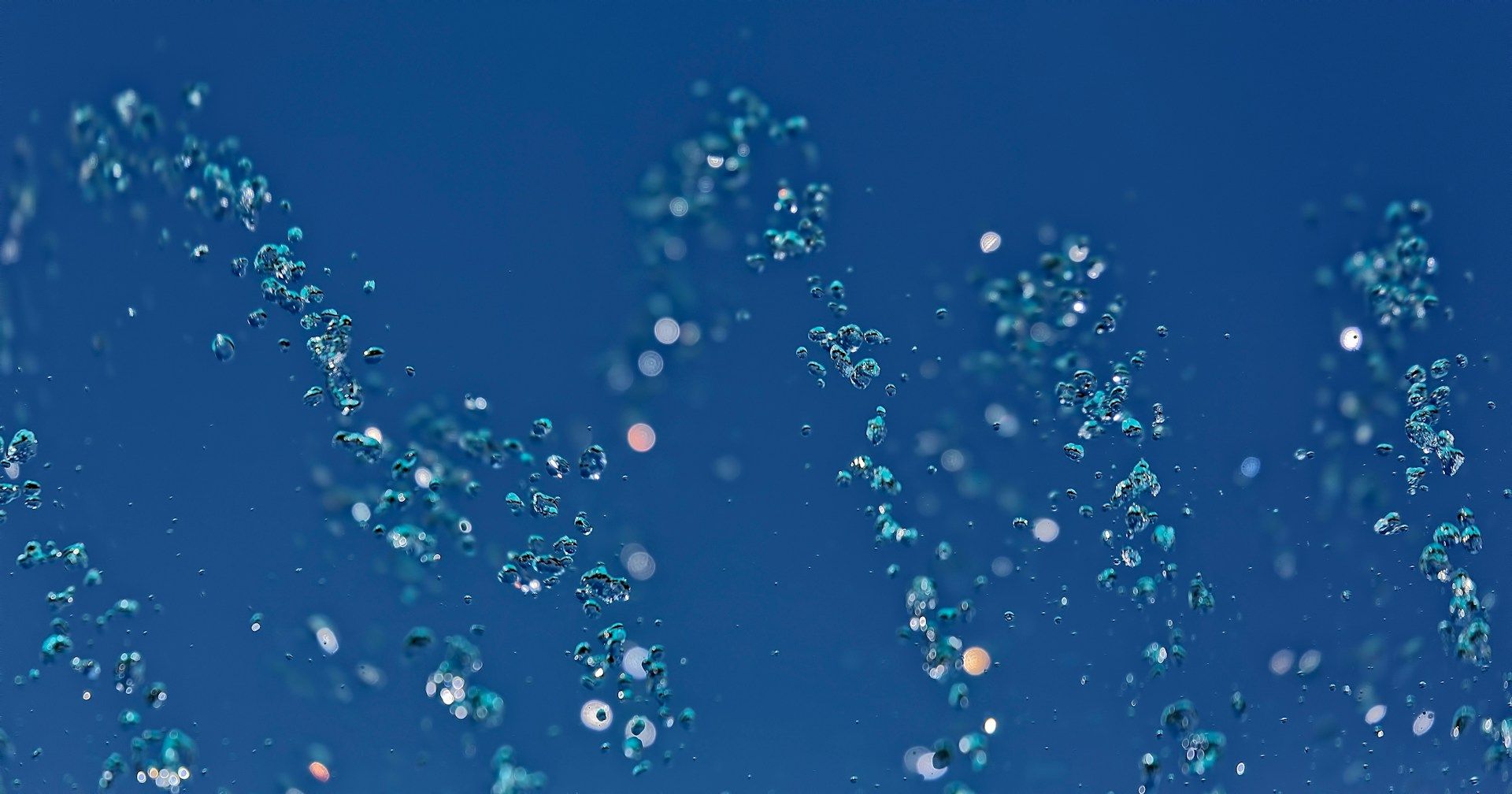 Air bubbles rise through blue water