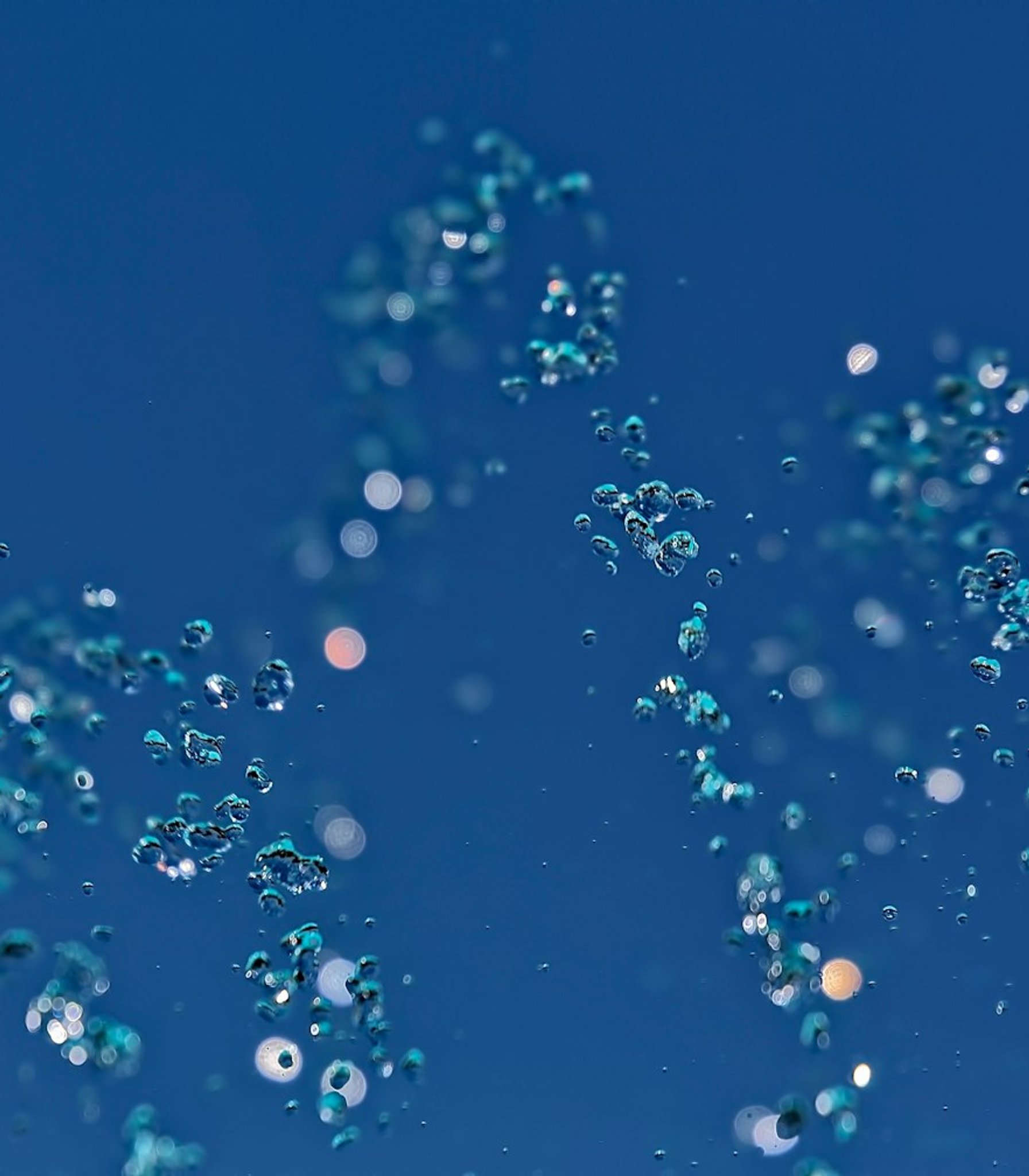 Air bubbles rise through blue water