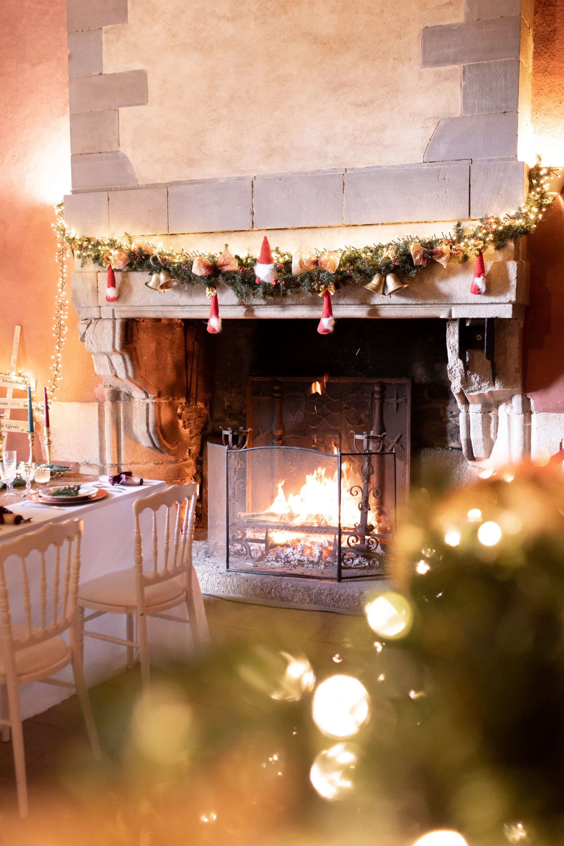 La cheminée de pierre habillée de sa guirlande de Noël