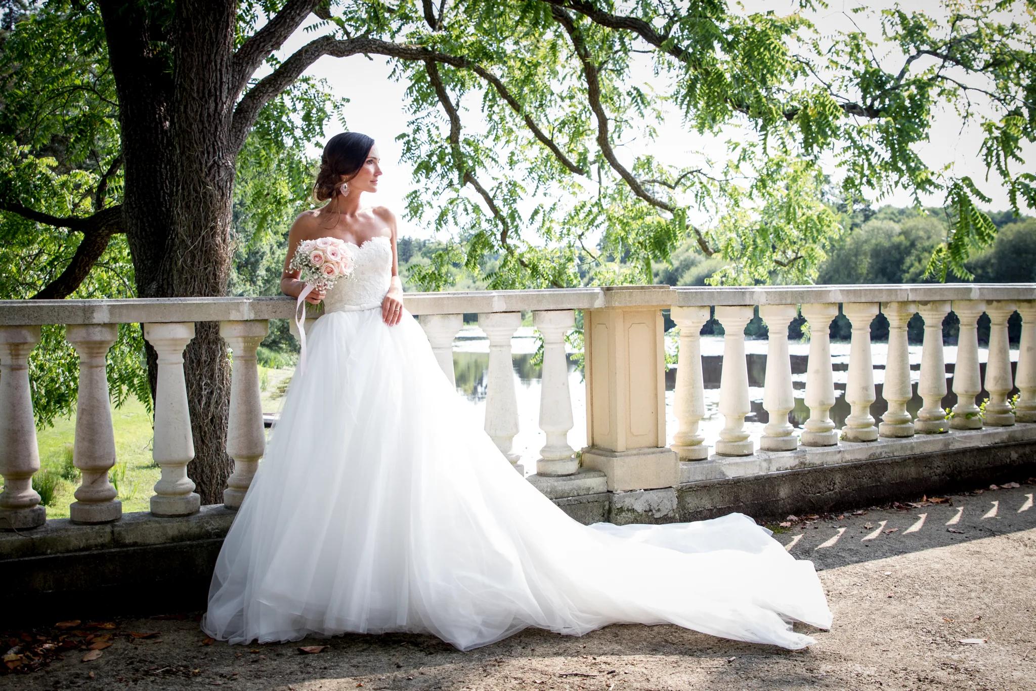 La mariée et sa longue traîne sur la terrasse à balustrade