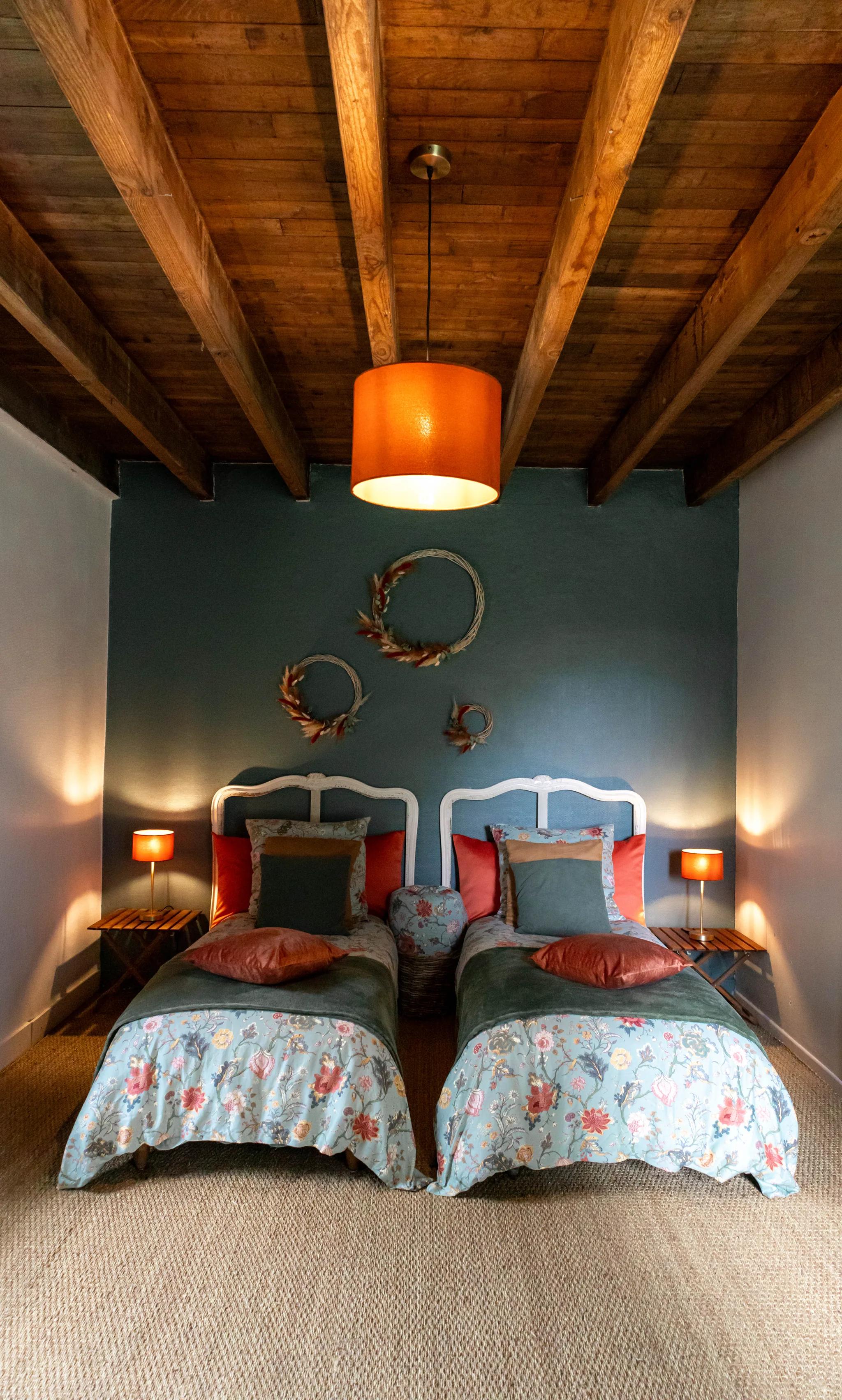 A cottage bedroom, its twin beds beneath the roof timbers