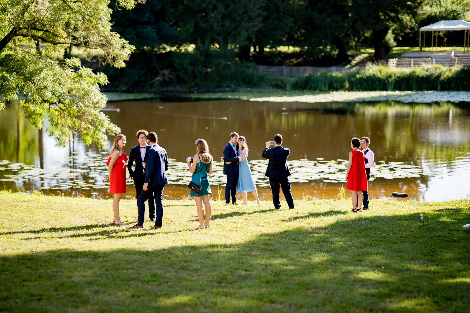 Invités en tenue de soirée au bord de l'étang, un verre à la main