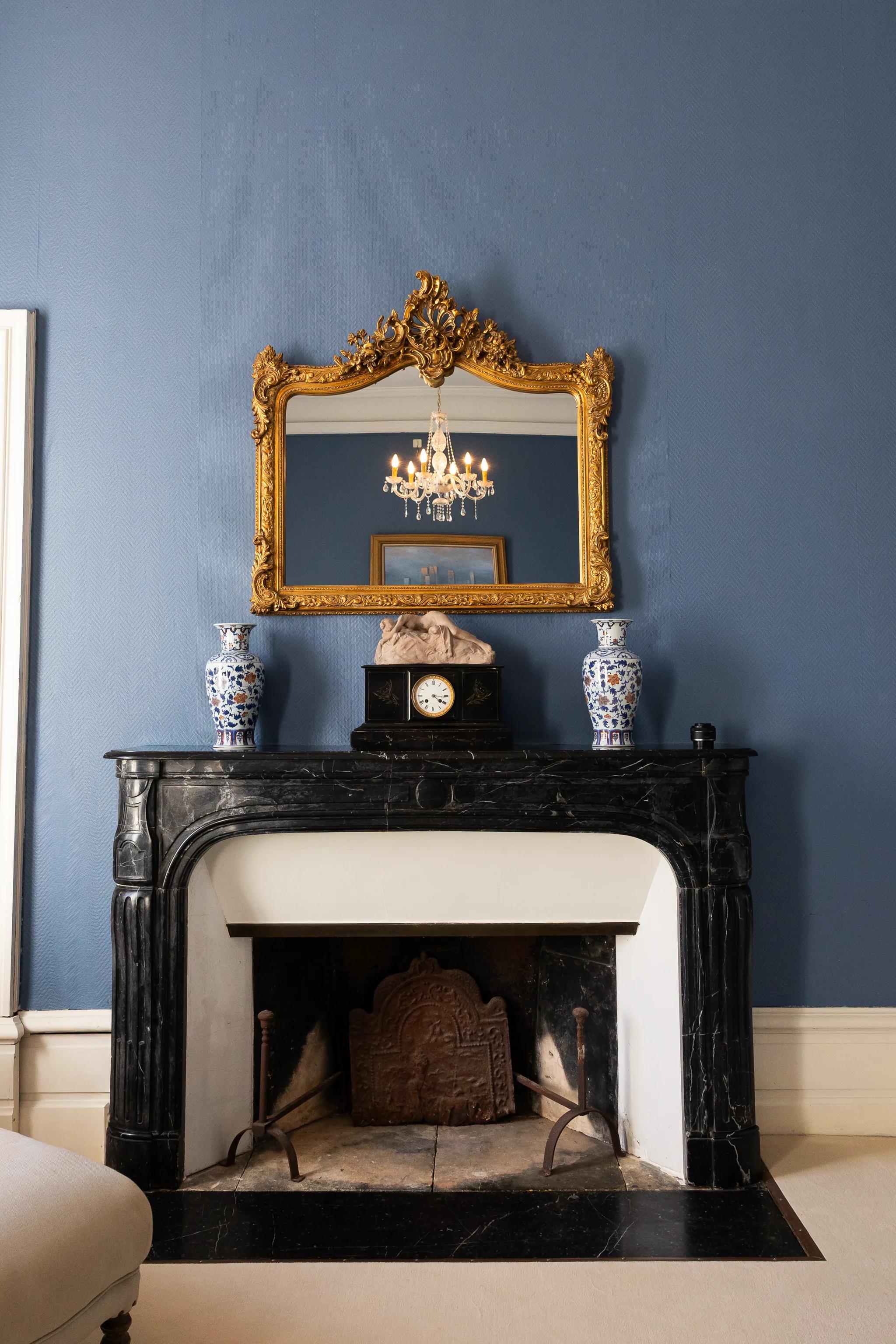 The black marble fireplace and its gilt mirror, in the bridal suite