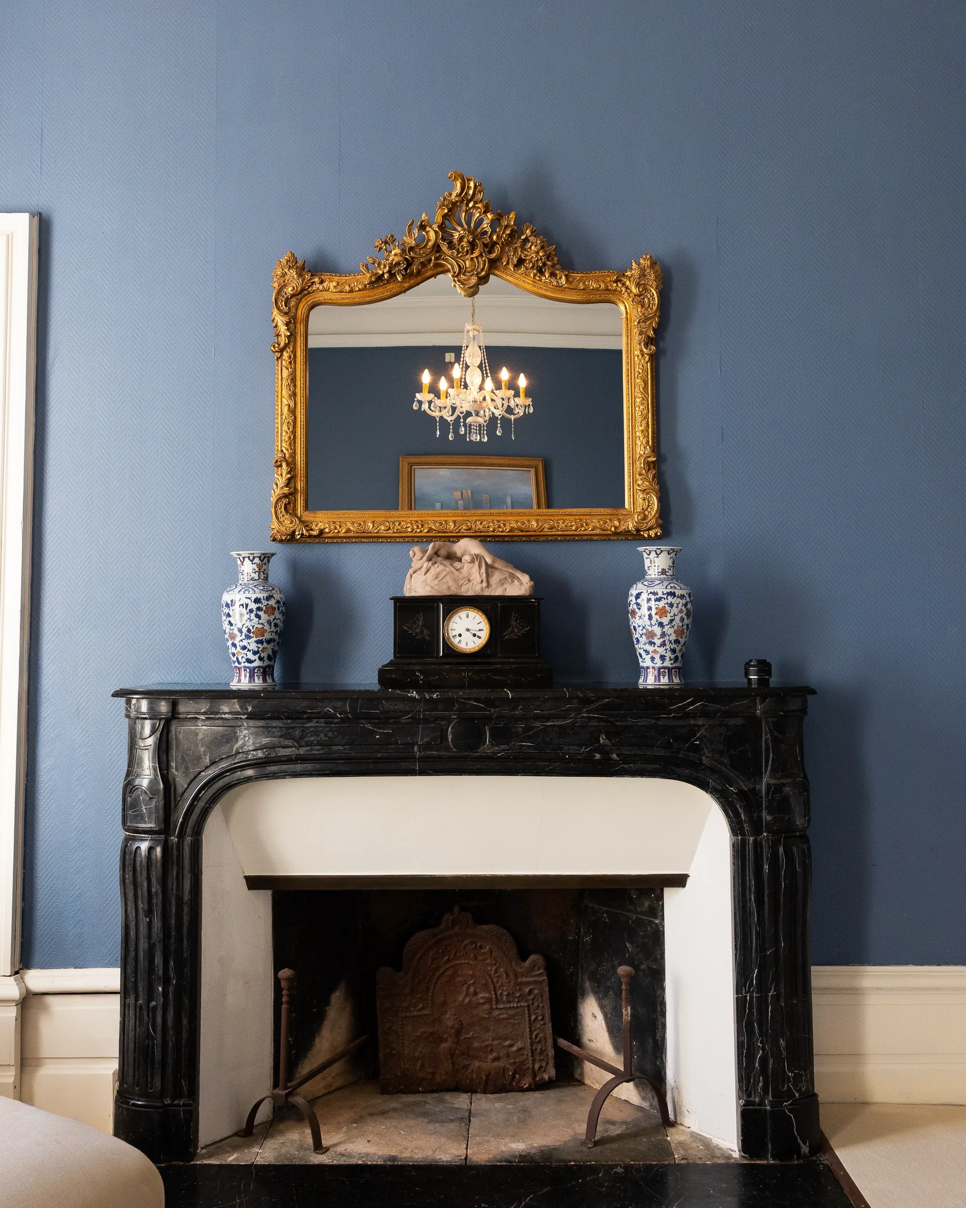 The black marble fireplace and its gilt mirror, in the bridal suite